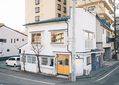 白い外壁と木の扉が見えたら、そこが「草のゆかり」。通りに面した大きな窓が目印で、店内では川沿いの景色を眺めながら、ゆったり過ごすことができます。